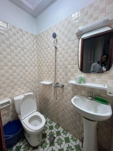 a man taking a picture of a bathroom with a toilet and sink at Beau Séjour in Yaoundé