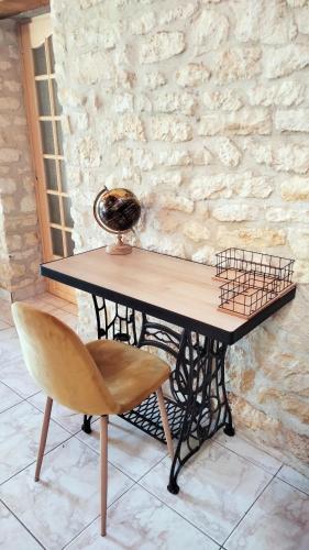 a table and a chair and a stone wall at Gîte 100m2- piscine partagée in Meursac