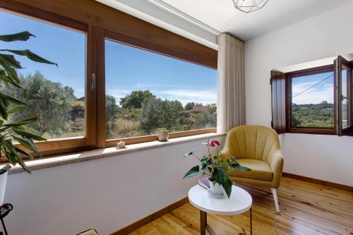 a living room with windows and a chair and a table at Casa Do Pião - Turismo Rural in Ansião