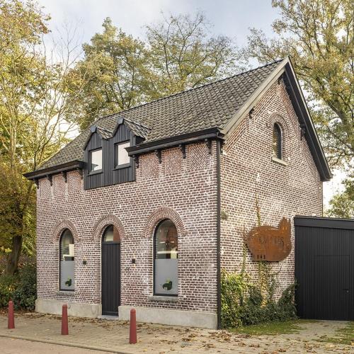 a red brick building with black windows and a garage at HoveniersHuis in Anzegem