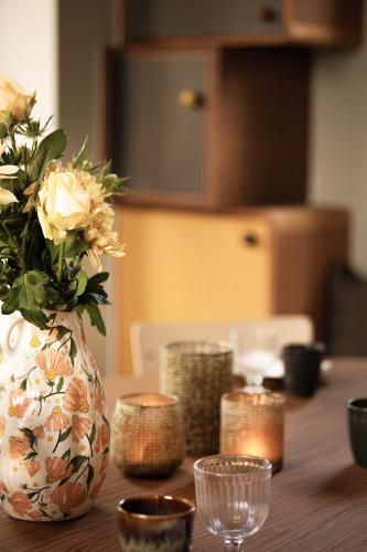 a vase with flowers on a wooden table with candles at HoveniersHuis in Anzegem