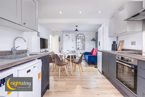 a kitchen with white cabinets and a dining room at Birmingham Group Stay in Birmingham