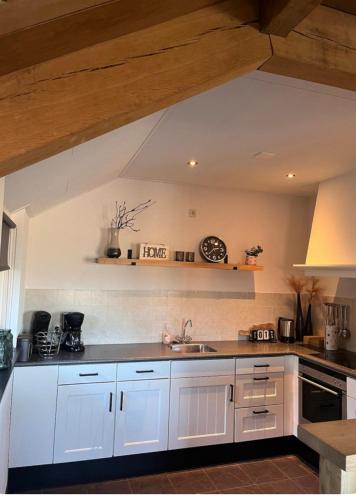 a kitchen with white cabinets and a sink at Vakantiewoning 't Linderveld in Rossum