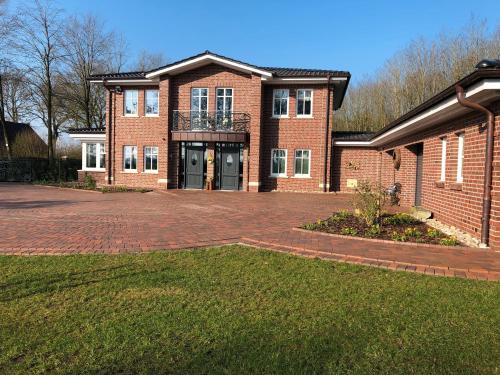 a brick house with a driveway in front of it at Ferienwohnung am Kronsberg in Bösel