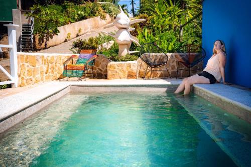 a woman sitting on the edge of a swimming pool at FLOR DE PARAISO BUNGALOWS in Montezuma