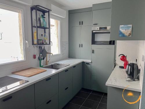d'une cuisine avec des placards gris, un évier et une fenêtre. dans l'établissement Sur les quais, Sète Centre-ville, à Sète