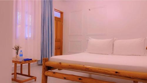 a bedroom with a bed with white sheets and a table at Evelina House in Boma la Ngombe