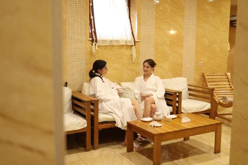 two women in white robes sitting on chairs in a room at СПА-Готель "RESPECT" in Skhidnitsa