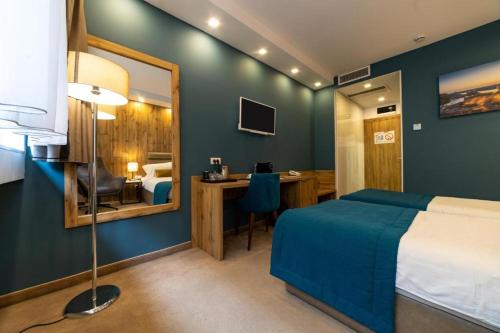 a bedroom with a bed and a desk and a mirror at MARK Hotel in Belgrade