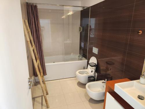 a bathroom with a toilet and a tub and a sink at Casa Rogel by Armação de Pêra with Heated Pool and Games Room in Alcantarilha