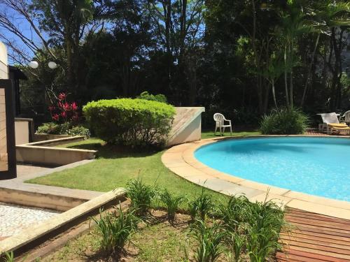 una piscina en un jardín con una silla junto a ella en Flat Confortavel no Morumbi, en São Paulo