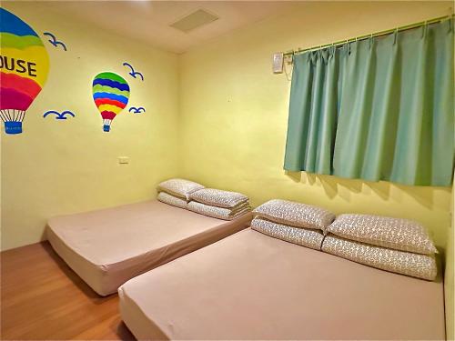 a room with two beds and a balloon mural on the wall at One House in Gongliao
