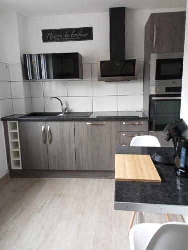 une cuisine avec des armoires en bois et un comptoir noir dans l'établissement Le Val Joyeux, à Colmar