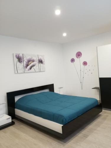 - une chambre dotée d'un lit avec des draps bleus et des fleurs sur le mur dans l'établissement Le Val Joyeux, à Colmar