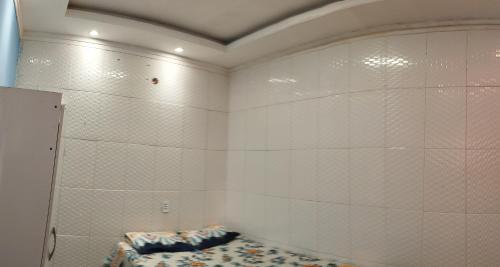 a room with white tiled walls and a mattress at Kitnet chegada de Porto B in Porto Seguro