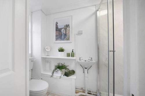 Un baño blanco con inodoro y lavabo. en 4 Bedroom Elegant House Near Peterborough City Center with Free Parking - Angus Suites by Contractor Lettings, en Peterborough