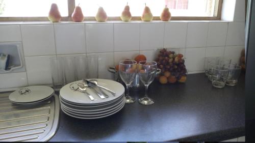 a kitchen counter with plates and wine glasses on it at Ocean Elephant Beach Apartment in Strand
