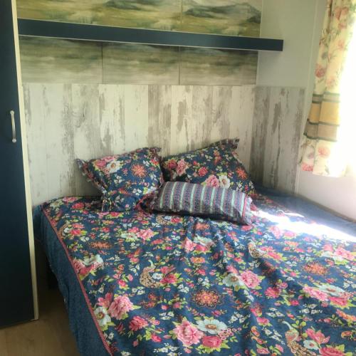 - un lit avec une couette à fleurs et 2 oreillers dans l'établissement Holidayhomepoujol mobile gite, à Montfermier