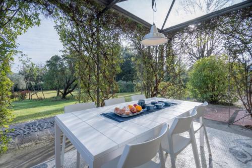 a white table and chairs with a bowl of fruit on it at Il Villino Del Collezionista With Pool, Pistoia in Pistoia