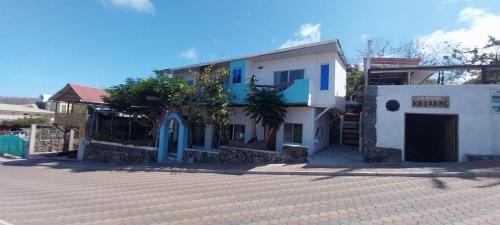 una casa blanca con puertas azules en una calle en Suite Arena, a pocos metros de la playa, en Puerto Baquerizo Moreno