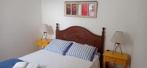 a bedroom with a bed with two night stands and two lamps at Apartamento no Centro Histórico in São João del Rei