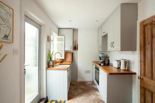 a small kitchen with white cabinets and a window at The Cycling Cottage, Surrey Hills AONB, Dorking in Dorking