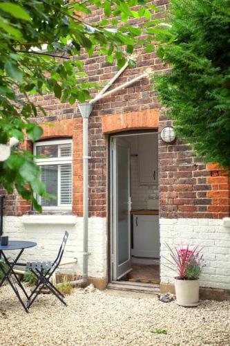 a brick house with an open door with a table and chairs at The Cycling Cottage, Surrey Hills AONB, Dorking in Dorking