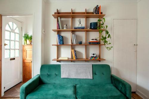 a green couch in a living room with a book shelf at The Cycling Cottage, Surrey Hills AONB, Dorking in Dorking
