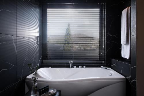 a white bath tub in a bathroom with a window at Athenian Riviera Hotel& Suites in Athens