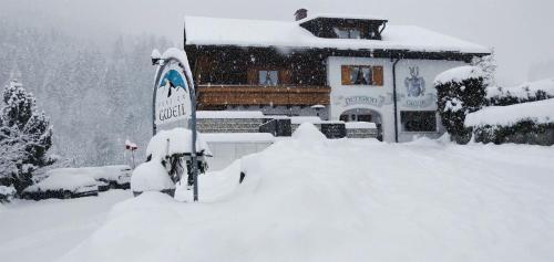 a snow covered house with a sign in front of it at Frühstückspension Gweil in Sankt Gallenkirch