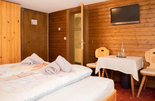 a room with two beds and a table and a television at Frühstückspension Gweil in Sankt Gallenkirch