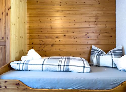 two beds in a room with a wooden wall at Frühstückspension Gweil in Sankt Gallenkirch