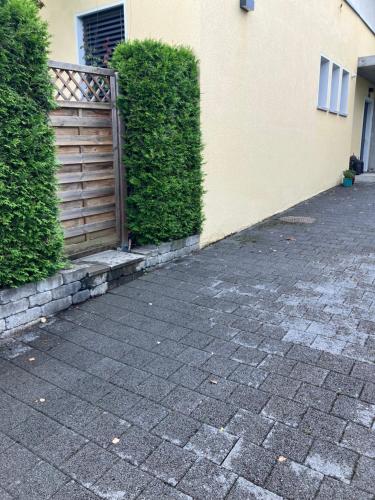 a brick sidewalk next to a building with a wooden gate at Studio with private garden & free parking in Köniz