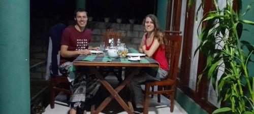 a man and a woman sitting at a table at Jungle Edge Cottage in Udawalawe