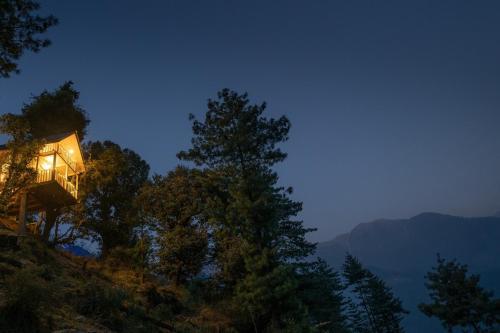 a lit up house on a hill at night at The Picturesque Treehouse in Tāndi