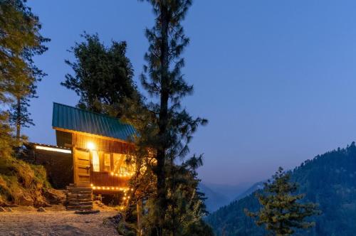 a house on the side of a mountain at night at The Picturesque Treehouse in Tāndi