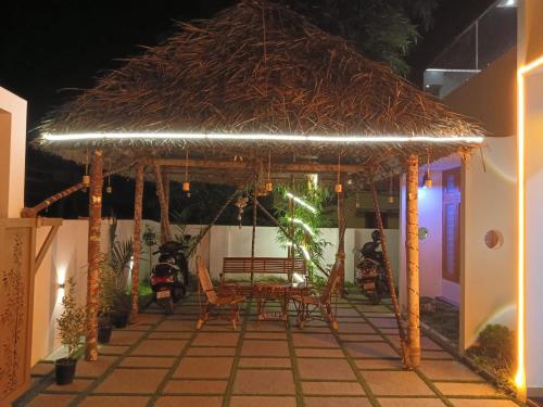 a table and chairs under a straw umbrella on a patio at Pepper Jazz Varkala in Varkala
