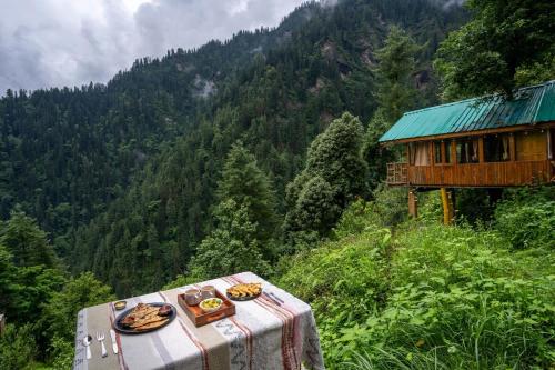 a table with plates of food on top of a mountain at Enchanting Cottage With Valley View By Bastiat Stays in Mandi
