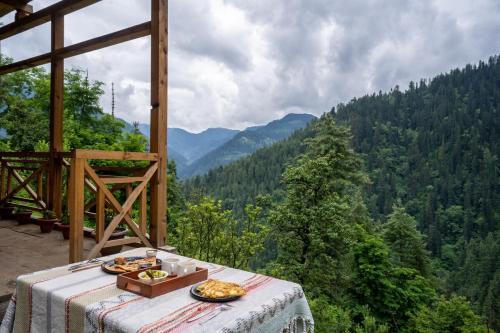 a table with a plate of food on top of a mountain at Enchanting Cottage With Valley View By Bastiat Stays in Mandi