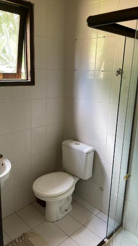 a white bathroom with a toilet and a window at Pouso in Paraty