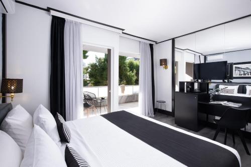 a hotel room with a bed and a desk and a window at Athenian Riviera Hotel& Suites in Athens