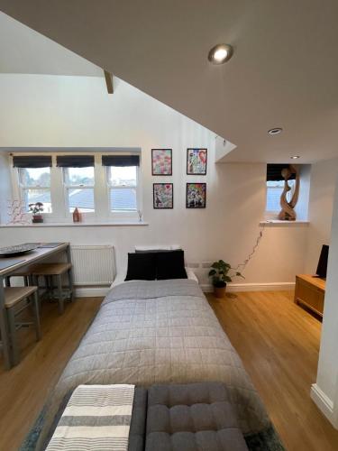 a bedroom with a bed and a desk and windows at Unique Loft Apartment St Austell in St Austell