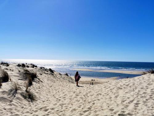 a person standing on a sandy beach next to the ocean at Mobil Home Moderne de 40m2 TOUT CONFORT Camping SIBLU Les CHARMETTES 785 La Palmyre Les Mathes in Les Mathes