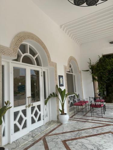 a white room with a door and a table and chairs at Hôtel Green Golf Hammamet in Hammamet