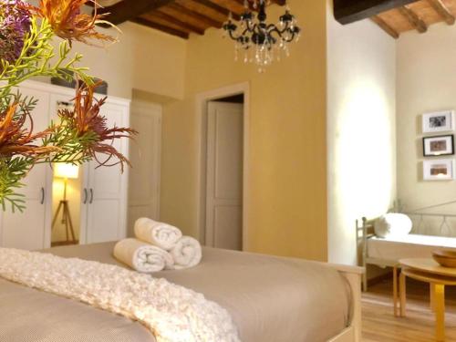 1 dormitorio con 1 cama con toallas y lámpara de araña en Fiori di Acaia, en Bagnoregio
