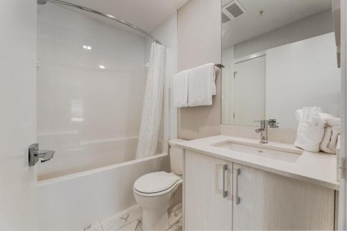a white bathroom with a toilet and a sink at Free Heated Parking, Close to DT, Pet Friendly in Calgary