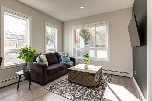 a living room with a brown couch and two windows at Free Heated Parking, Close to DT, Pet Friendly in Calgary