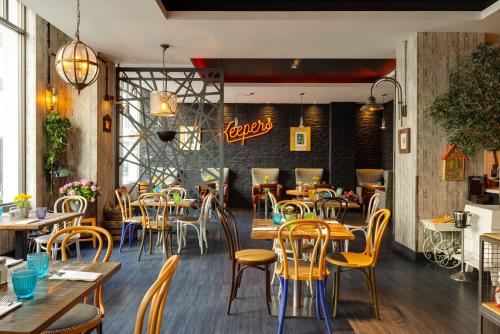 a restaurant with wooden tables and chairs and a brick wall at Novotel London Tower Bridge in London