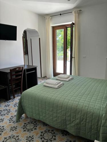 a bedroom with a green bed and a desk and a window at La Perla dei Gemelli in Agerola