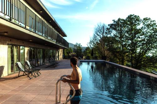 a young man standing next to a swimming pool at Estrela Serenity - Resort in Folgosinho